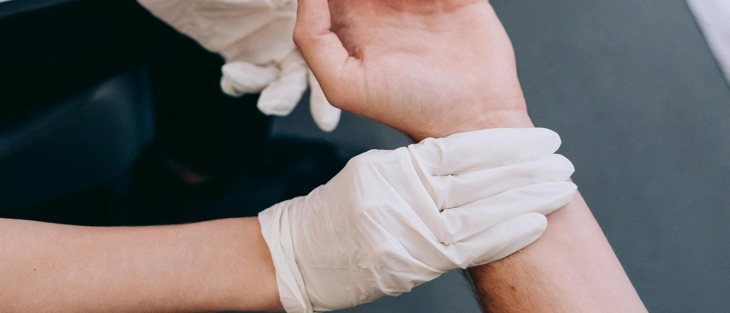 Gloved hands holding a person's wrist and hand