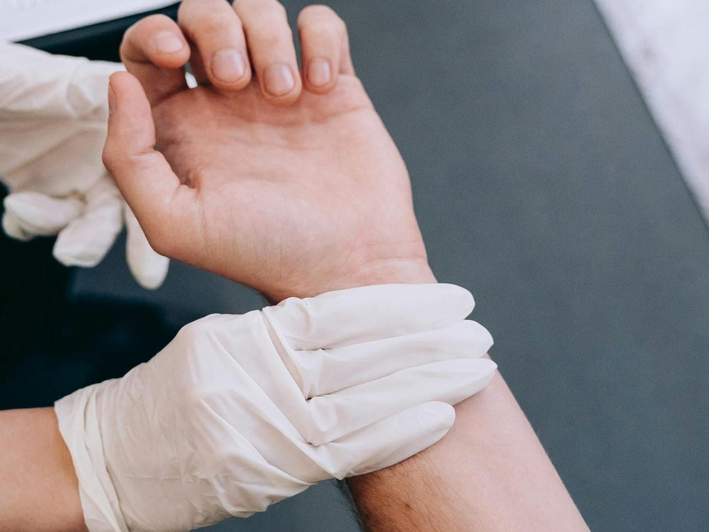 Gloved hands holding a person's wrist and hand